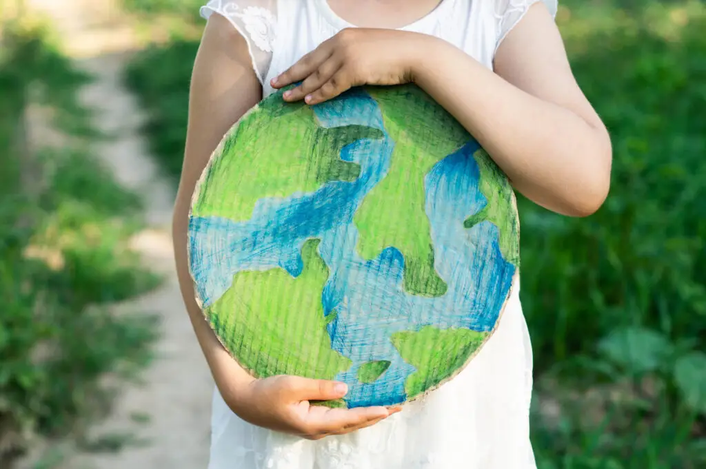 child holding cardboard craft of globe